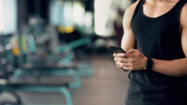 A man using smart fitness apps on his phone at the gym for workout tracking.