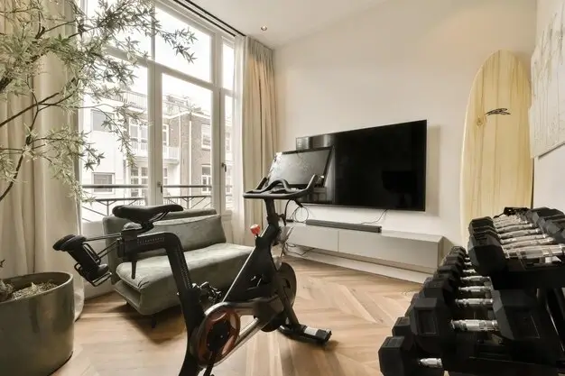 Modern small space gym with a stationary bike, dumbbells, and a sleek home setup.