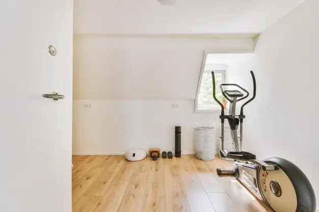 Minimalist small space gym with an elliptical machine and compact workout equipment.