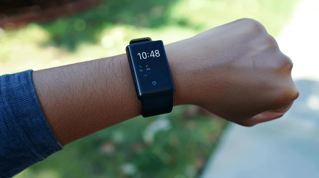 A Fitbit smartwatch on a wrist displaying time and heart rate in the Whoop vs Fitbit comparison.
