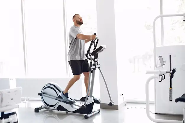 Man using an elliptical good for weight loss in the gym.