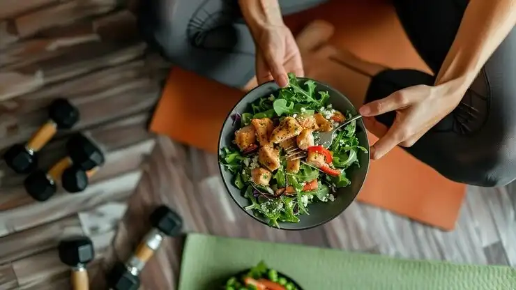 Athlete eating a protein-rich salad after a biohacking workout for strength and recovery.