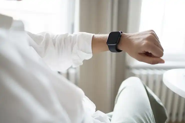 Person relaxing at home while checking a smart fitness tracker for health metrics and daily activity.